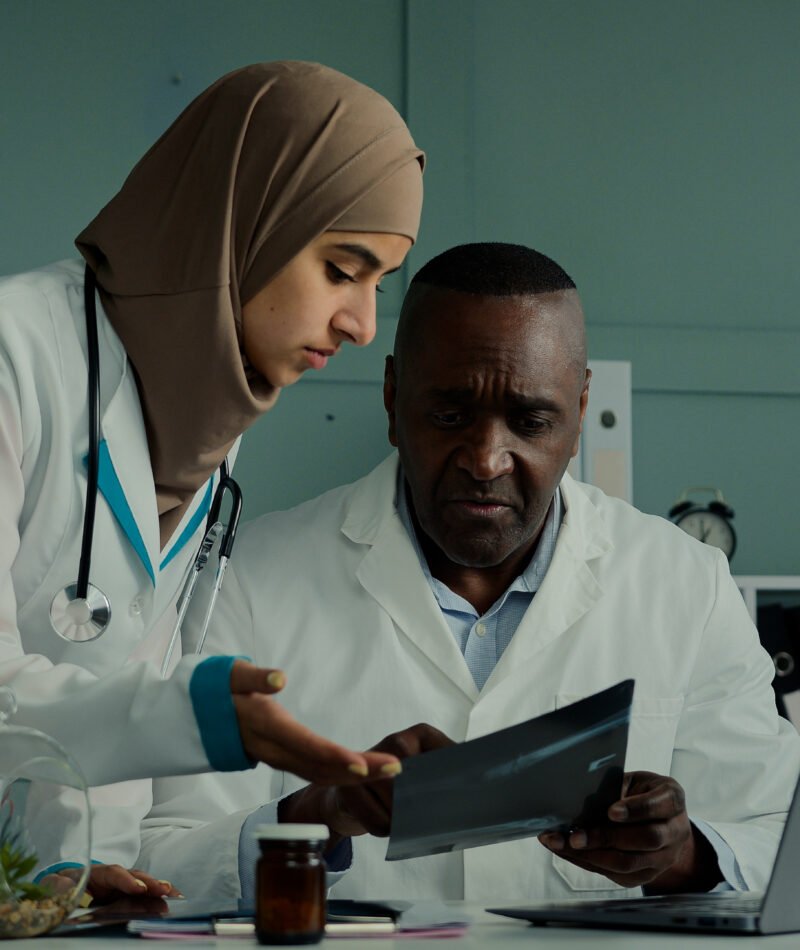 Multiracial doctors colleagues discuss teamwork african man and arabian woman two professional medical workers talk about healthcare check MRI scan use computer app doing online research X-ray results